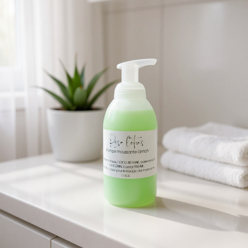 Green foaming pump soap bottle for sensitive skin on bathroom counter with towels and plant