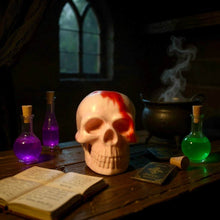 Charger l&#39;image dans la galerie, Vegetable glycerin soap shaped like a skull with a red streak, surrounded by potion bottles, an open book, and a smoking cauldron on a wooden table.
